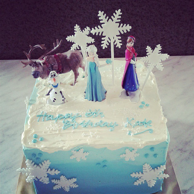Snowflake themed cake with Frozen toppers Sven, Olaf, Elsa, Anna. Made by Little Collins Cafe. Source