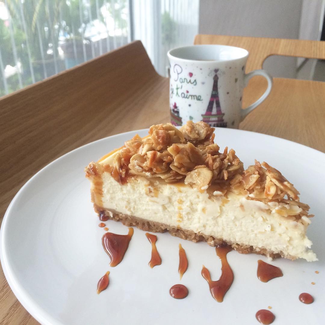 Cheesecake topped with roasted almonds and coconut, served with melted gula Melaka by Vanilla Pods. Source. 