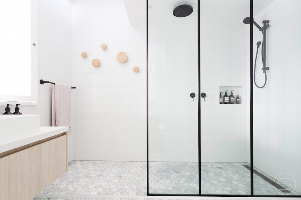 White bathroom with black shower fixtures. Design by Spinzi