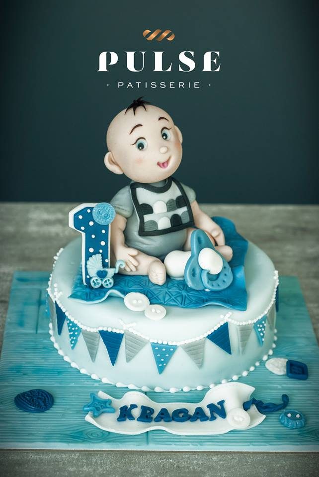 A round cake nicely wrapped with fondant and topped with a figurine of a baby boy. Made by: Pulse Patisserie Singapore - Recommend.sg