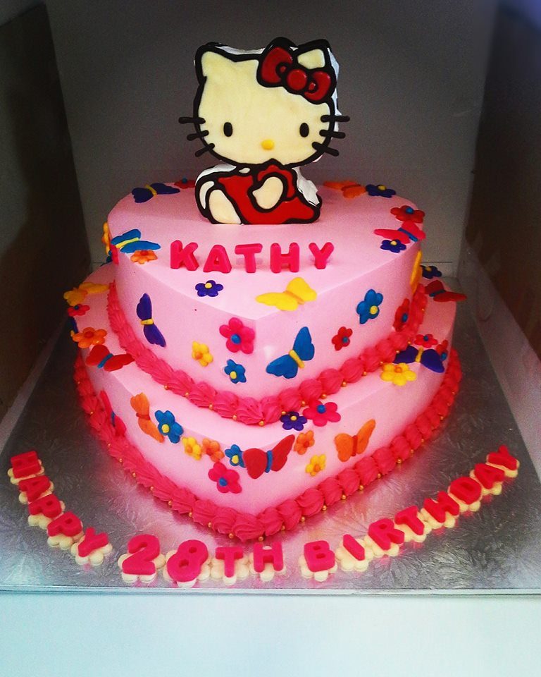 A two-tiered heart shaped cake with pink buttercream frosting and Hello Kitty cake topper. Made by: Naomi Kitchen. Source