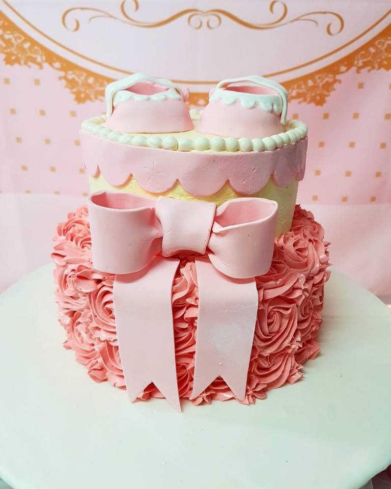 A two-tiered cake with a pair of pink booties. Made by: Little Sprinkles Singapore - Recommend.sg