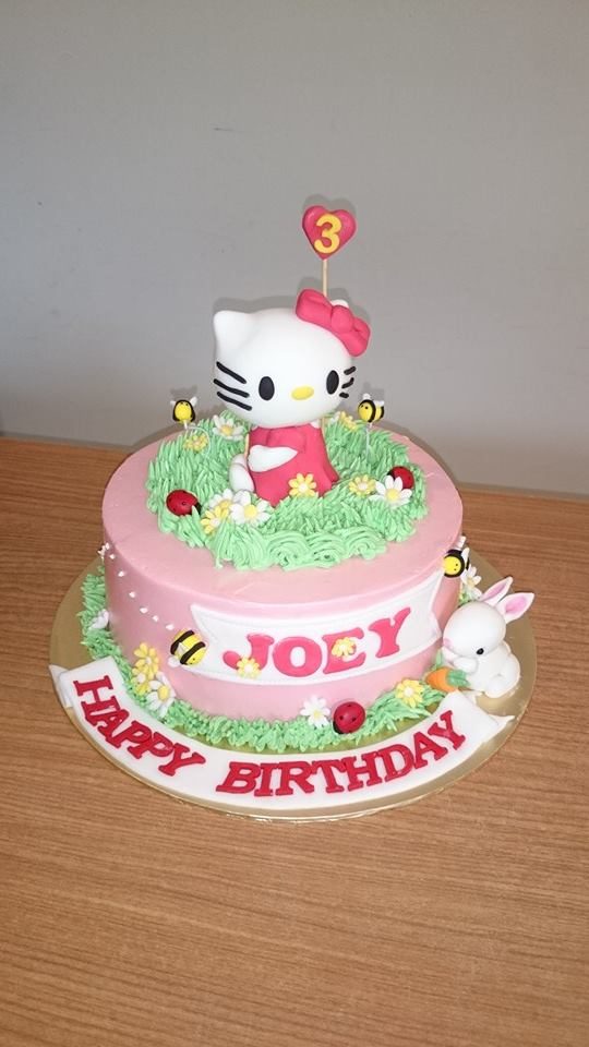 A Hello Kitty figurine on a round cake frosted and decorated with buttercream and other edible decorations. Made by: My Fat Lady Cakes and Bakes. Source