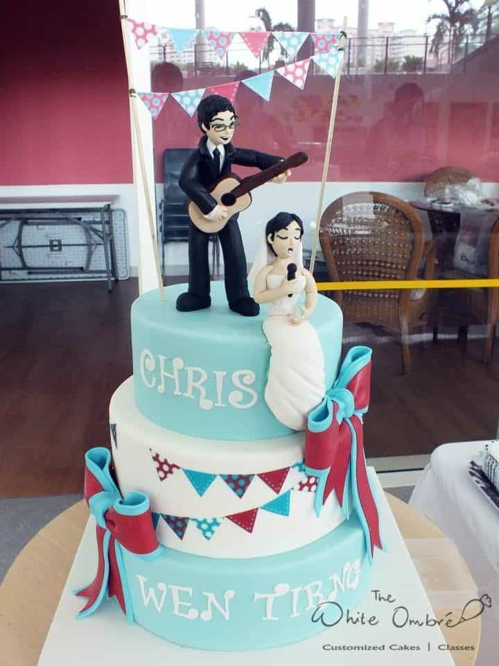 A modern pink and blue themed wedding cake with edible figurines of the bride and groom. Made by: The White Ombre.Source