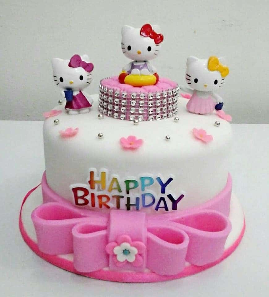 White and pink coloured round cake with three Hello Kitty figures on top. One of which, sits on a raised small piece of cake decorated with edible diamonds. Made by : Eats & Treats Bakery.Source