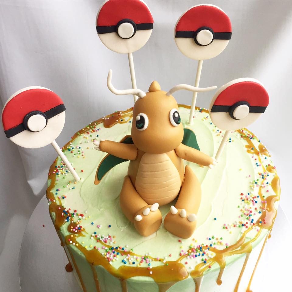 A round cake with caramel drip topped with edible Dragonite and Pokeball pops is simple but nice. Custom cake by Corine and Cake.Source