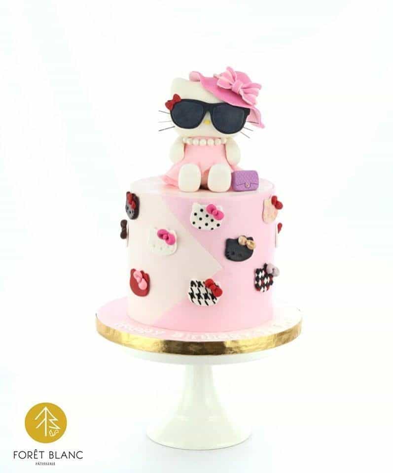 A simple tall, round cake can stand out from the crowd with the addition of a Hello Kitty topper wearing a hat and a sunglasses. Made by: Foret Blanc Patisserie.Source