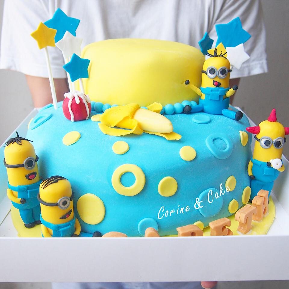 A two-tiered round cake decorated with fondant and edible Minion figurines. Made by: Corine and Cake.Source