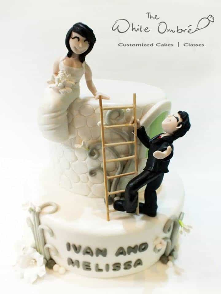 A two-tiered round cake with fondant detailings and edible figurines of the bride and groom.Made by: The White Ombre.Source