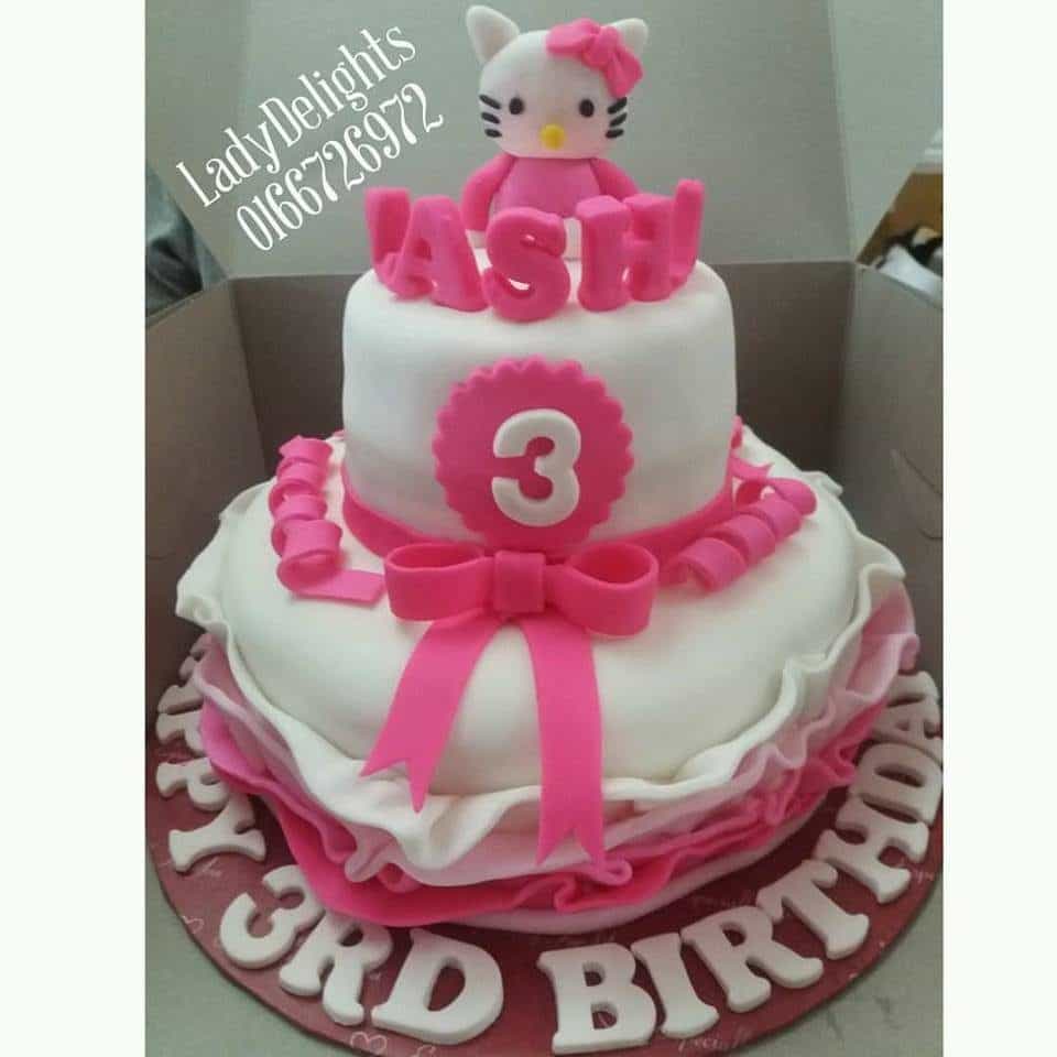 Two tiered birthday cake decorated with fondant ruffle and ribbon, plus a super cute Hello Kitty figure on top. Made by: Ladydelights Bakery .Source