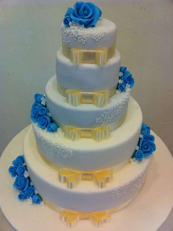 A five-tiered banded cake with blue sugar flowers and hand-drawn lace detailings. Made by: Bonheur Patisserie.Source