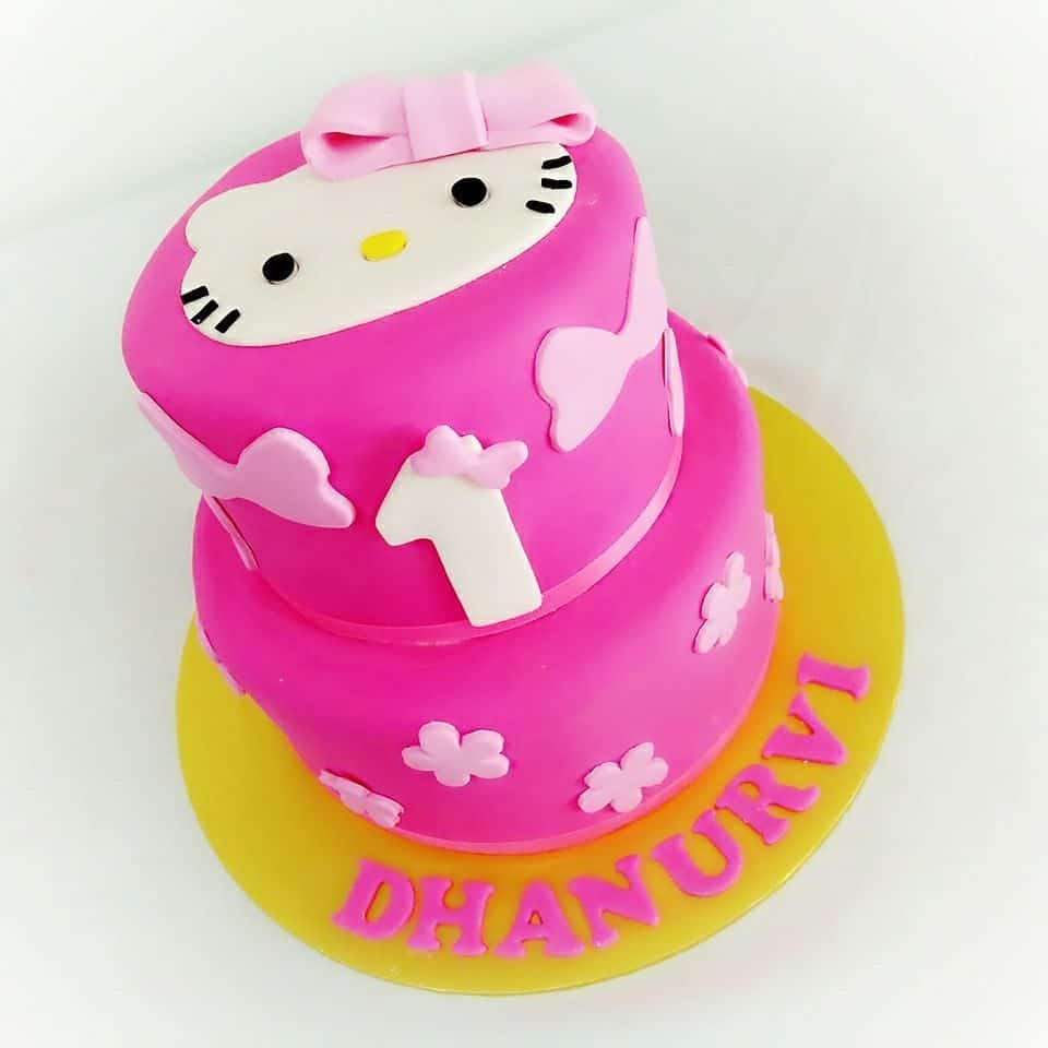 Two-tiered round pink cake with yellow base, ribbon and Hello Kitty fondant cutout sticked to the surface.Made by : Eats & Treats Bakery.Source