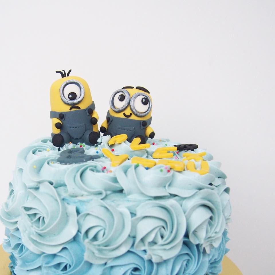 A round cake with blue rosette buttercream frosting with edible Minion figurines on top.Made by: Corine and Cake.Source