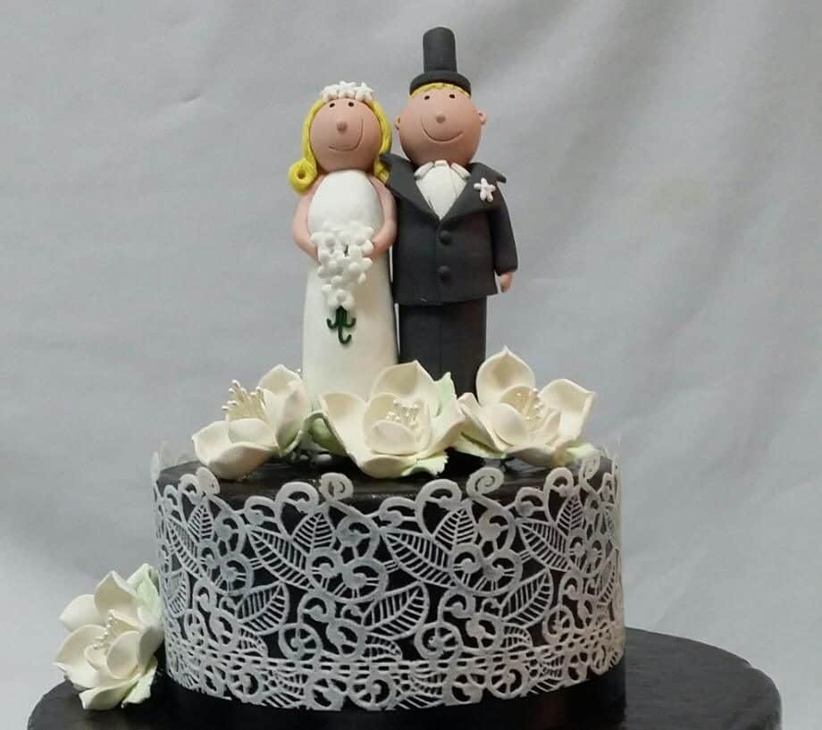 A black fondant cake with white lace detailings and handmade sugar flowers.Made by: Temptations Cakes.Source