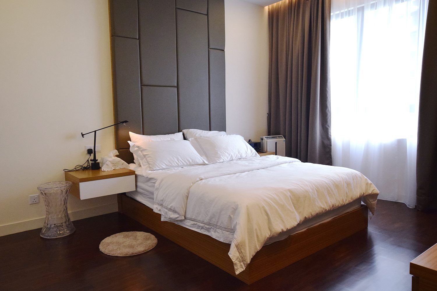 Floating bedside tables and dark wood flooring for this condominium in Windows On The Park, KL